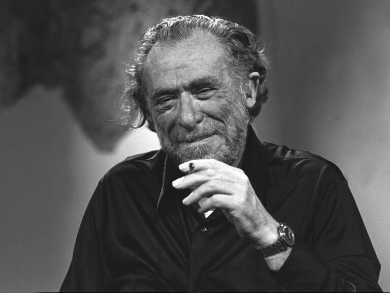 Bukowski smiling holding a cigarette